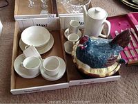 Photo showing the rooster soup tureen with ladle alongside white china coffee pot and various cups and saucers in a box.