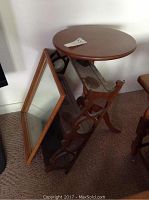 Photo showing the small round wooden occasional table with smooth top and the wooden framed rectangular mirror leaning against the wall beside a decorative wooden wall shelf.