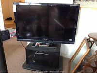 Full view of Sony TV mounted on black stand with glass doors