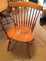 Front view of one chair showing contoured seat and spindle back