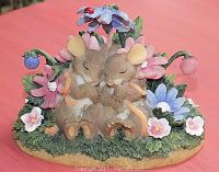 Front view showing two hugging mice among flowers on grassy base