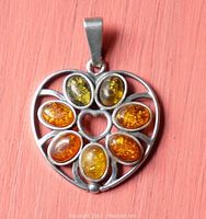 Front view of the sterling silver heart-shaped pendant with seven oval multicolored amber stones and an open heart center.