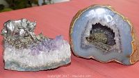 Two quartz crystal rock figures on a red surface, one amethyst cluster with pewter bear, one geode with pewter mining scene.