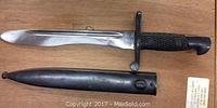 Side and top view of bayonet blade and matching steel scabbard showing polished finish and blade fuller.