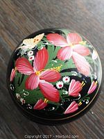 Top view of the round lacquerware box showing the floral design in pink, red, and white flowers with green leaves and butterfly accents on a black background.