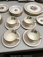 Photo showing four porcelain cups with matching saucers and bread plates with gold filigree and Tudor Rose floral decoration