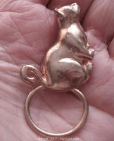 Front view of gold tone cat-shaped brooch with circular glasses holder ring at bottom, showing smooth reflective surface with slight wear.