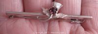 Front view of the sterling silver Scottish thistle pin showing detailed leaves and a purple glass stone at center.