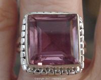 Close-up of square amethyst stone with checkerboard bezel setting on sterling silver band.