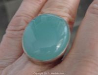 Top view of the ring showing the oval polished blue agate stone and surrounding sterling silver bezel setting on finger.