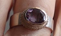 Close-up image showing the amethyst stone set on the sterling silver band worn on the finger.