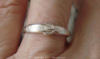 Ring worn on finger showing the engraved buckle design on the band.