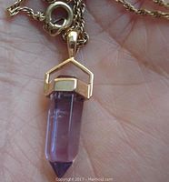 Close-up of the light amethyst quartz pendant shaped like a pointed bullet with a gold-tone bail marked 925, showing the translucent purple quartz.