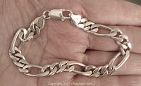 Vintage sterling silver Figaro link bracelet shown held in hand, displaying the full length and link style.