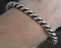 Close-up photo of the vintage twisted sterling silver rigid bangle bracelet worn on wrist, showing the twisted design and texture.