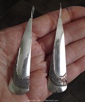 Front view of the vintage sterling silver earrings showing the smooth polished surface and textured dot pattern near the bottom.