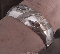 Photo of the stamped sterling silver bangle bracelet on wrist showing the grooved band and geometric stamped design with brush and shiny finishes.