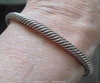 View of the twisted sterling silver bangle on wrist showing its size and style.