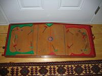 Top view of wooden tabletop hockey game with red and green players, wooden frame, and painted rink surface