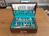 Full view of the flatware set displayed in open wooden canteen showing forks, spoons, and knives with ornate Heritage pattern handles.