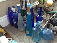Blue glass bottles and a round blue glass decorative object on the floor near wall