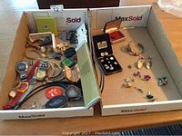 Box with multiple costume jewelry pieces including untested wristwatches, earrings, and rings spread across two trays