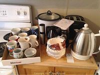 Photo showing 4-slice toaster, Salton cooker/steamer, Hamilton Beach electric kettle, coffee grinder, coffee mugs, Misto spray bottle, coffee filters on kitchen counter
