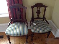Front view of two Eastlake style chairs with striped upholstered seats, showing carved wooden backs and turned legs.
