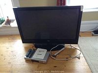 Overview of Hitachi TV on stand with Sony CD player, remotes, cables