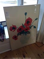 Framed John Lander poppies poster leaning against window with light reflection