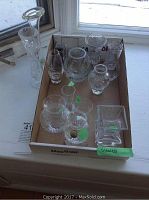 Box containing multiple crystal and glass vases of various shapes and sizes, with some green stickers.