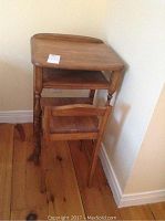 View of early telephone table with matching chair, showing the side and front angles, loose note on table top visible.