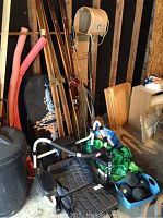 Photo showing ab exerciser in black and white frame, wooden cross country skis, ski poles, pool noodles, and other miscellaneous items in garage.