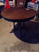 Photo of the round wooden table showing its worn surface and the pedestal base.