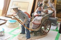 Side view of porcelain figurine showing the man pulling the rickshaw and the woman seated inside.