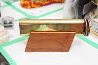 Front view of brass kaleidoscope on wooden stand on a table with other items blurred in background.