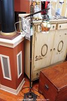 Full view of adjustable metal floor lamp with iridescent glass shade on wooden floor