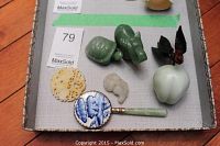 All six items arranged in tray: two green jade animal carvings, small pale jade carving, yellow openwork medallion, porcelain hand mirror with jade handle, and stone peach with metal leaves and berries.