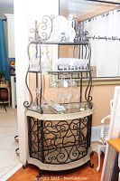 Full view of the glass and metal wine rack stand displaying glassware and decanters on the shelves.