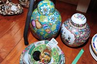 Photo showing the two ginger jars with lids and stack of small bowls focusing on top decoration and artwork detail