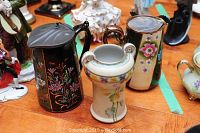 Photo of two lidded ale pitchers and a decorative vase showing floral patterns and craftsmanship
