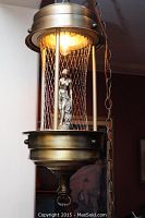 Front view of the vintage rain lamp with the nude goddess figurine inside the cylindrical frame and warm light on.