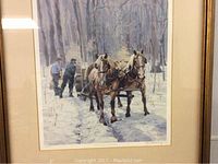 Close-up of the framed print showing two horses and men in a snowy forest scene reflecting the detailed artwork.