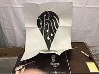 Photo showing large folded poster from collection on table with open Eric Clapton book visible