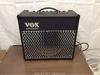 Front view of black Vox AD30 guitar amplifier with metal grille and logo on front.