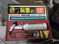 Ronson Varaflame butane torch kit in original metal box showing the white butane fuel canister, torch body, and brass attachments.