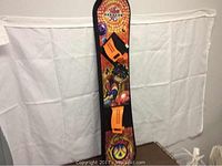 Full view of the junior snowboard displaying Bakugan Battle Brawlers themed graphics and orange bindings.