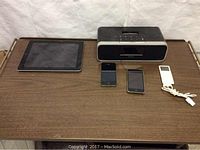 Full lot on wooden surface showing iPad, two iPods, iPhone, and iHome docking station with missing cables