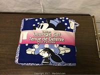 Photo of the front folded pajama set with visible Minnie Mouse graphic and pink label indicating "Ladies Lounge Set".