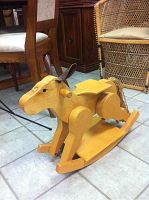 Front side view of the wooden rocking horse showing the horse's body, round wooden handles as reins, and the curved rockers.